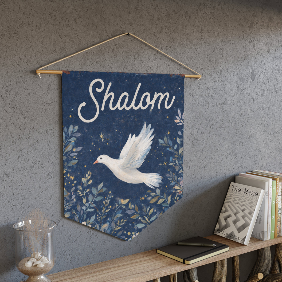 Navy blue Shalom dove wall pennant hanging above a bookshelf on a gray textured wall