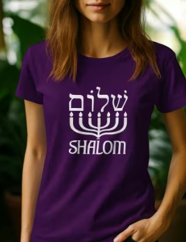 Purple Shalom t-shirt with white Hebrew lettering above a menorah, worn by a woman near green plants