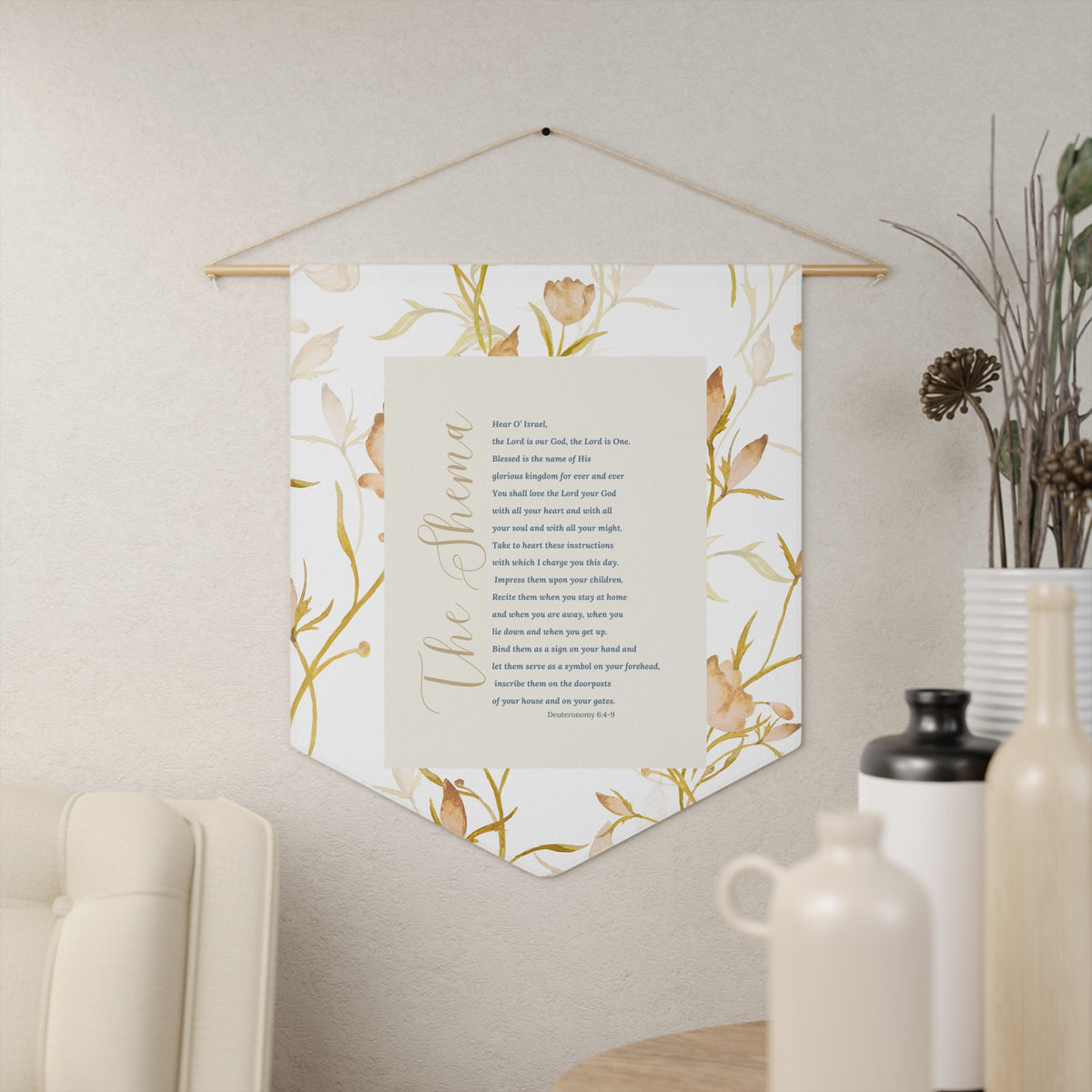 The Shema Deuteronomy 6:4-9 wall pennant with the passage framed by soft gold florals, hanging in a living room