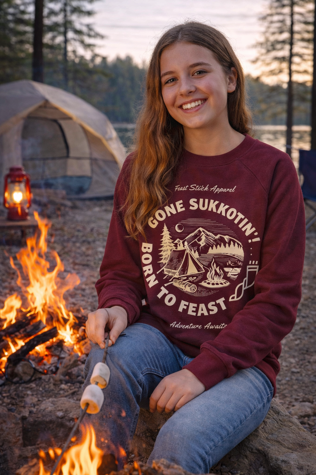 Maroon Gone Sukkotin' Born to Feast youth sweatshirt worn by a smiling teen girl roasting marshmallows by a campfire