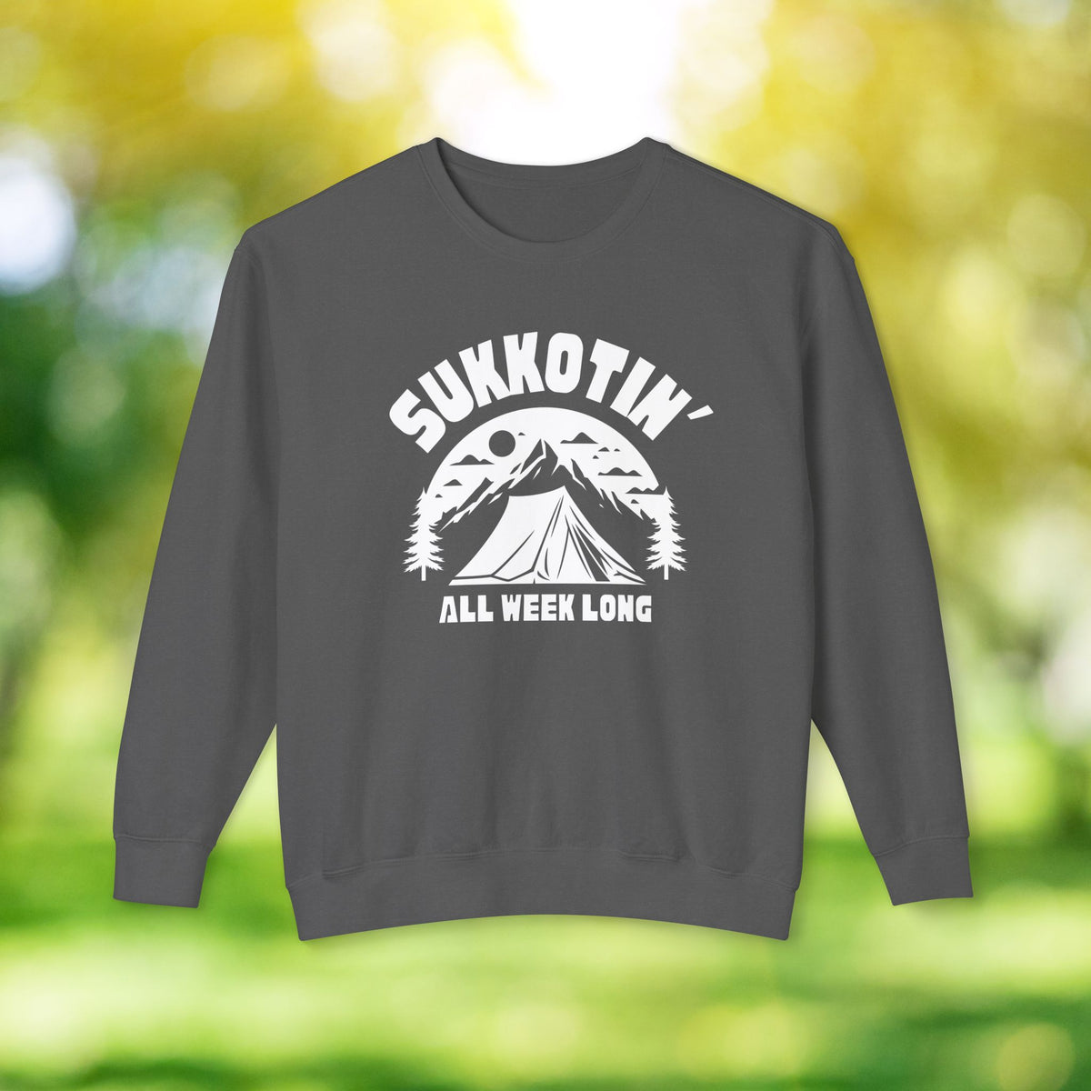 Pepper gray Sukkotin' All Week Long sweatshirt with a white tent and mountain graphic, shown against a blurred green background