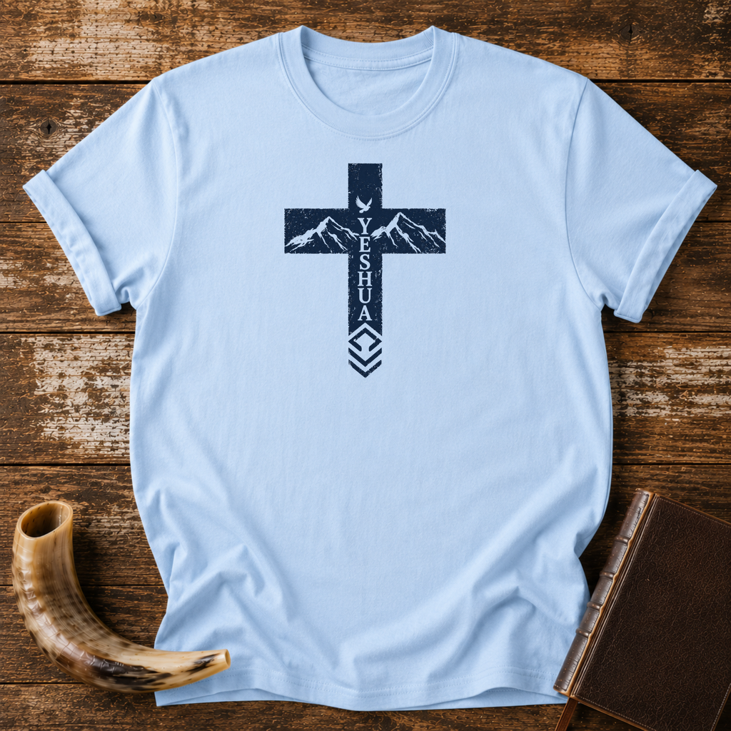 Light blue Yeshua cross t-shirt with mountains and a dove in the cross, laid flat with a shofar and Bible
